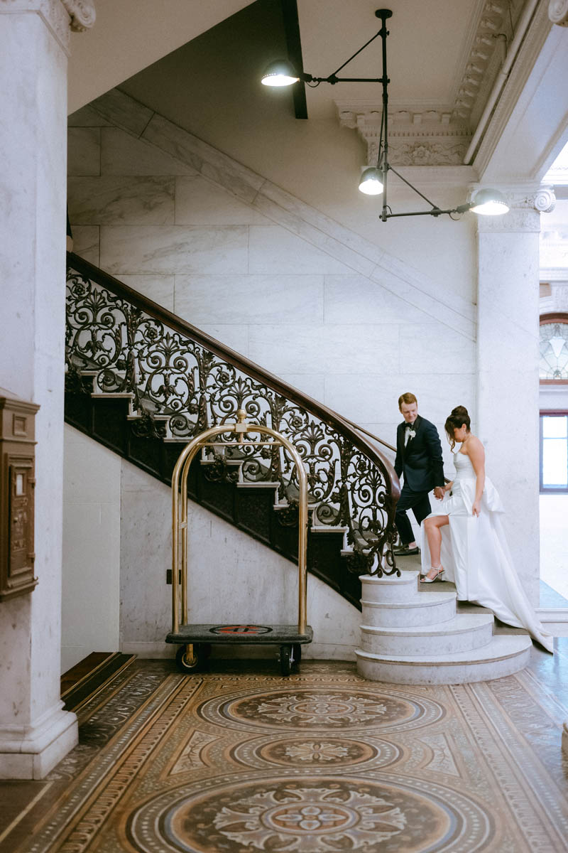 Candid moment of bride and groom walking up the ornate staircase