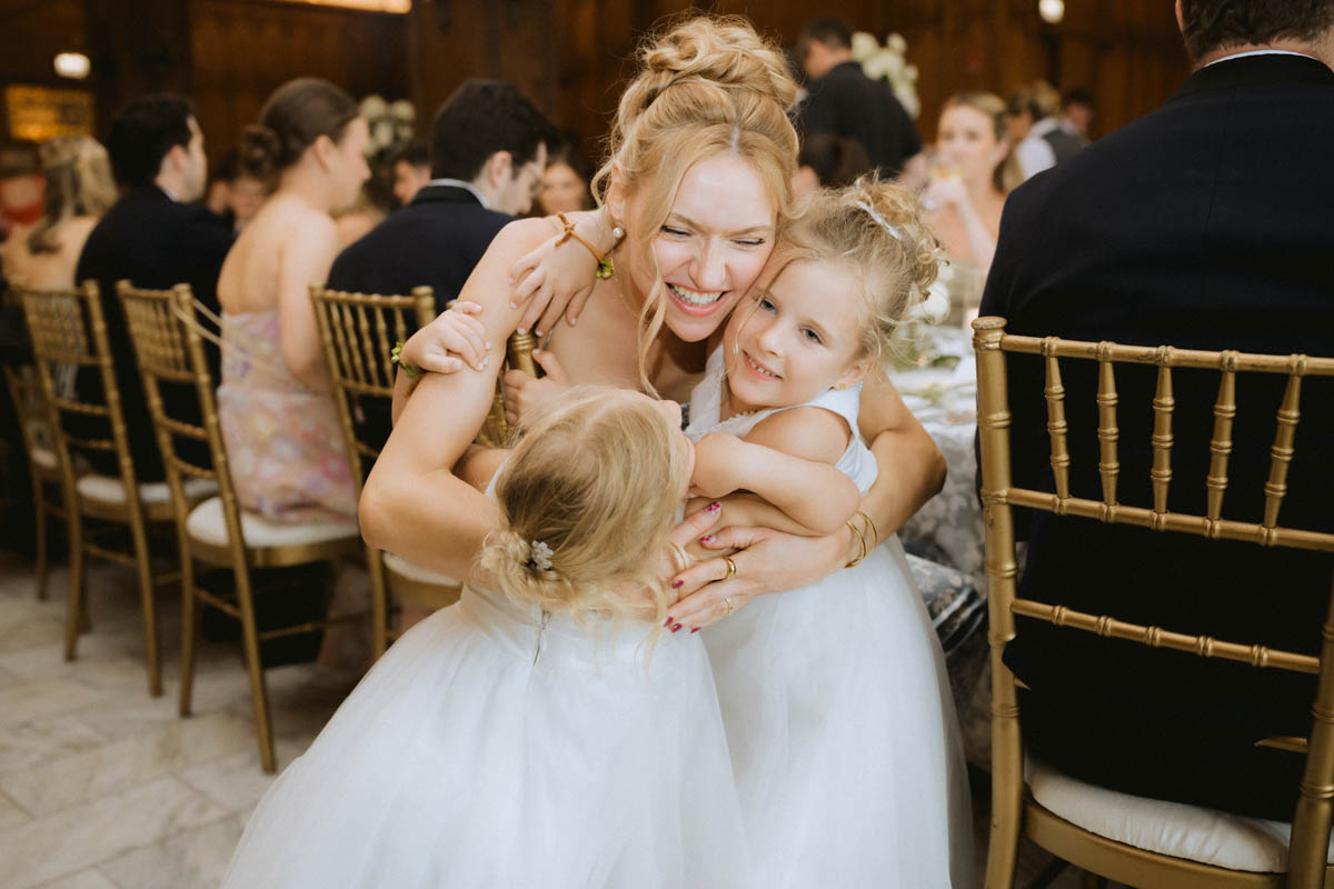 Flower girls hug wedding guest