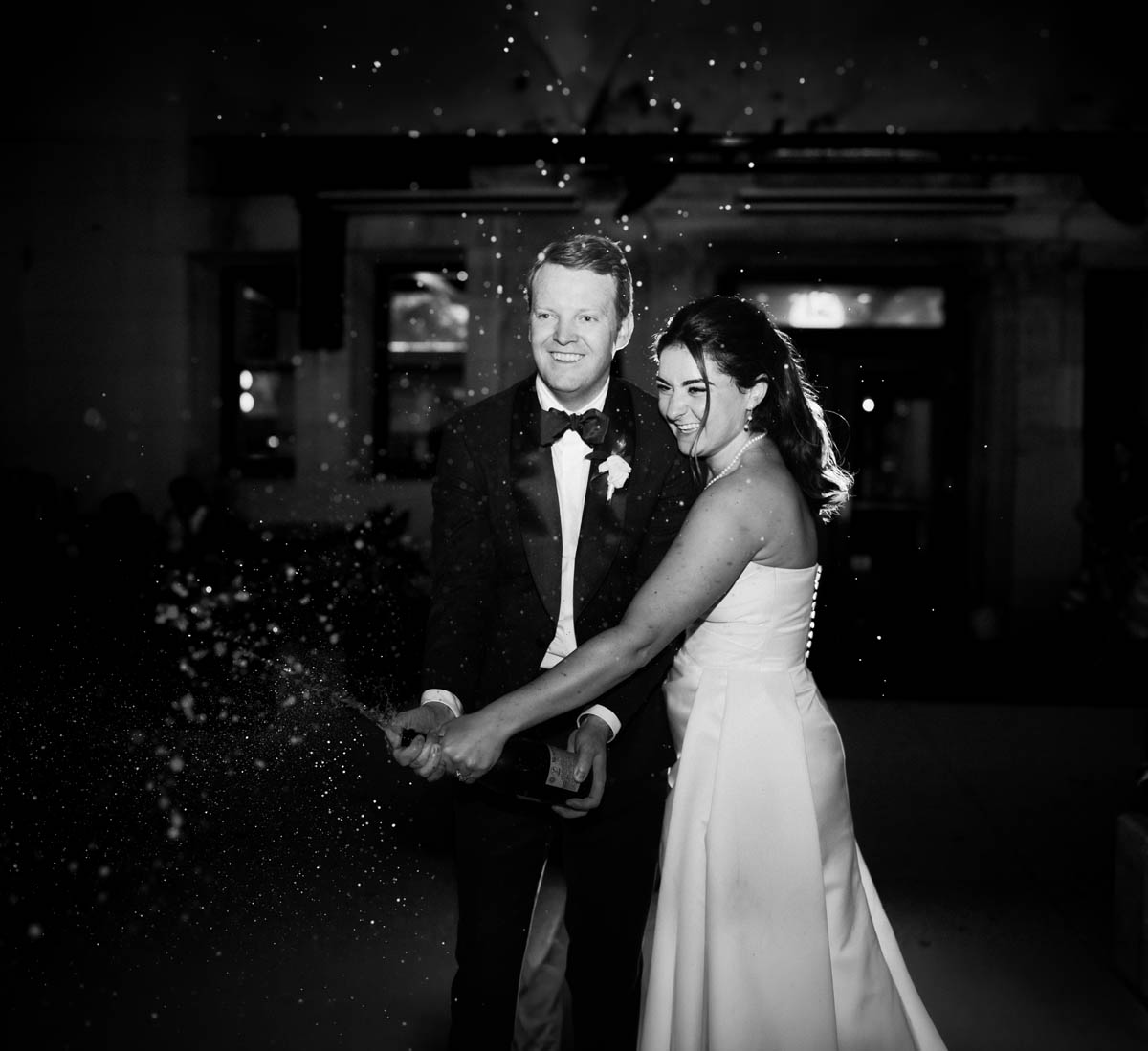 Bride and groom popping the champagne at their Chicago Athletic Association Hotel after their wedding reception