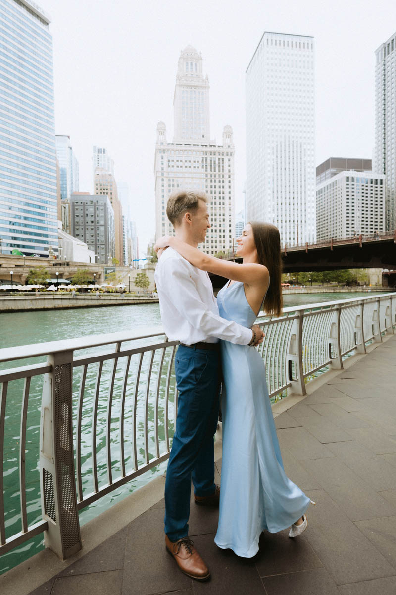 Engaged couple embracing by the Chicago riverwalk.